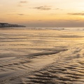 reflets dorés sur le sable mouillé de la plage d'Ault au soleil couchant