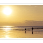 Promeneurs sur la plage d'Ault au soleil couchant