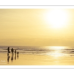 Promeneurs sur la plage d'Ault au soleil couchant