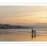 Promeneurs sur la plage d'Ault au soleil couchant