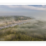 France, Somme (80), Baie de Somme, Saint-Valery-sur-Somme, la brume matianel se dissipe peu à peu et laisse appaitre le village et les hauteurs du cap hornu avec la chapelle des marins et le chenal de la Somme bordé des quais de promenade (vue aérienne) // France, Somme (80), Baie de Somme, Saint-Valery-sur-Somme, the morning mist gradually dissipates, revealing the village and the heights of Cap Hornu with the sailors' chapel and the Somme channel lined with pedestrian quays (aerial view)