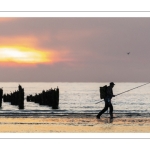 Pêcheur à la ligne sur la plage entre les bouchots