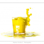 GlaÃ§on qui tombe dans un verre de jus d'orange (boisson jaune) et provoque une Ã©claboussure.