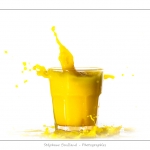 GlaÃ§on qui tombe dans un verre de jus d'orange (boisson jaune) et provoque une Ã©claboussure.